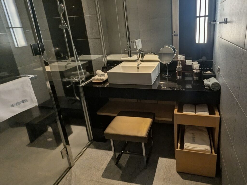 高級感あふれる石造りのダブルシンクと、大きな鏡が特徴のエクシブ湯河原離宮の洗面台 / Luxurious stone-top double sink vanity with a large mirror at XIV Yugawara Rikyu.