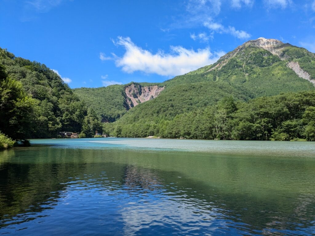 焼岳の噴火で生まれた神秘的な大正池と、背景にそびえる雄大な焼岳 / Mysterious Taisho Pond created by the eruption of Mt. Yakedake, with the majestic volcano in the background.