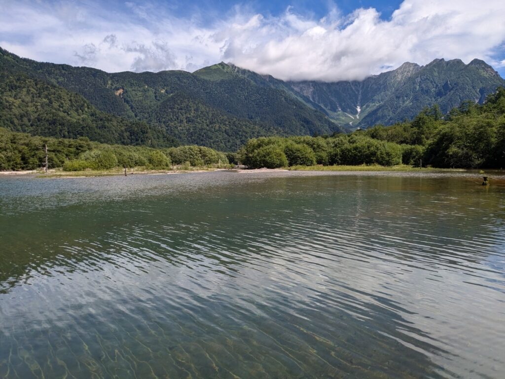 大正池の澄んだ水面に映る、穂高連峰の絶景と幻想的な立ち枯れの木々 / Breathtaking view of the Hotaka Range and mystical withered trees reflected in the clear water of Taisho Pond.