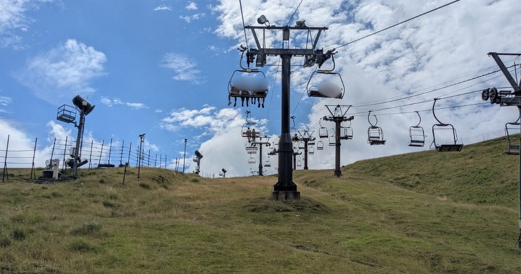 Café 360へと向かうリフトから望む青空と青々とした山頂の絶景 (View of the blue sky and lush summit from the lift bound for Café 360)
