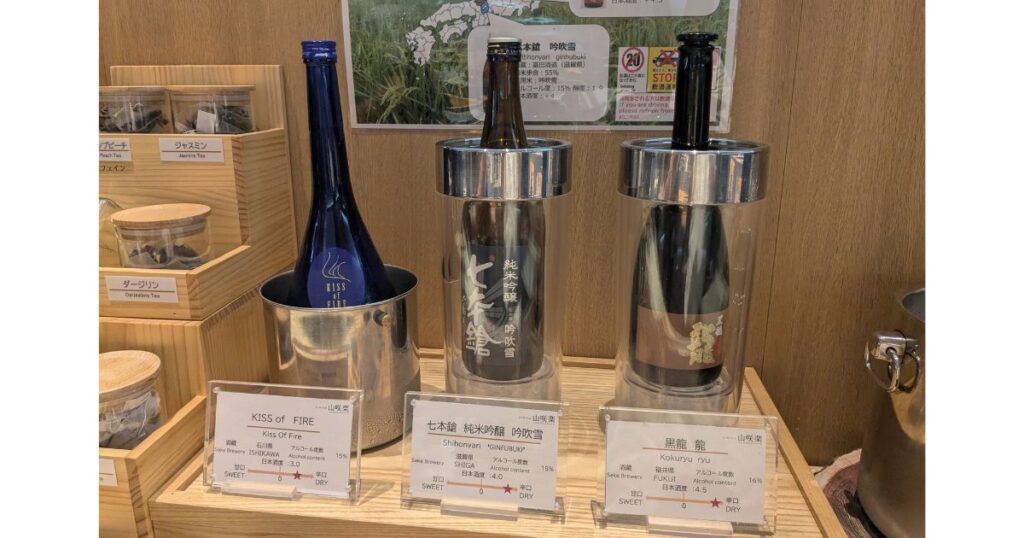 湯元館の朝食で楽しめる日本酒ボトルと説明ポップ (Local sake bottles and explanation cards at Yumotokan breakfast buffet)
